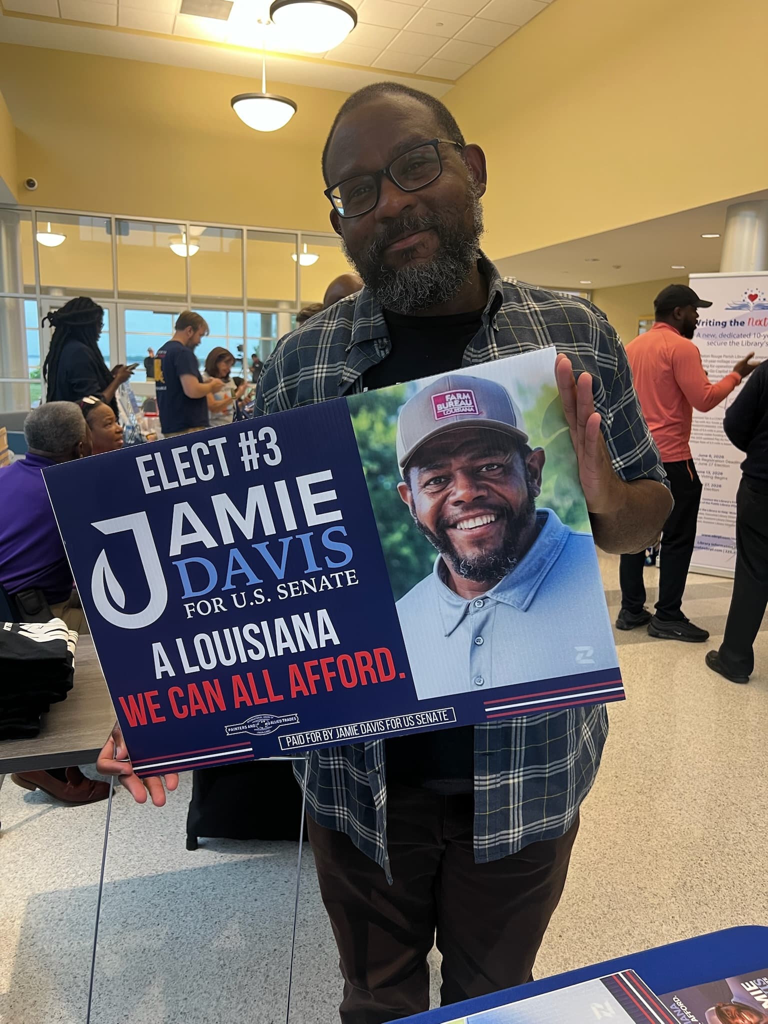 A supporter holding a Jamie Davis for U.S. Senate yard sign