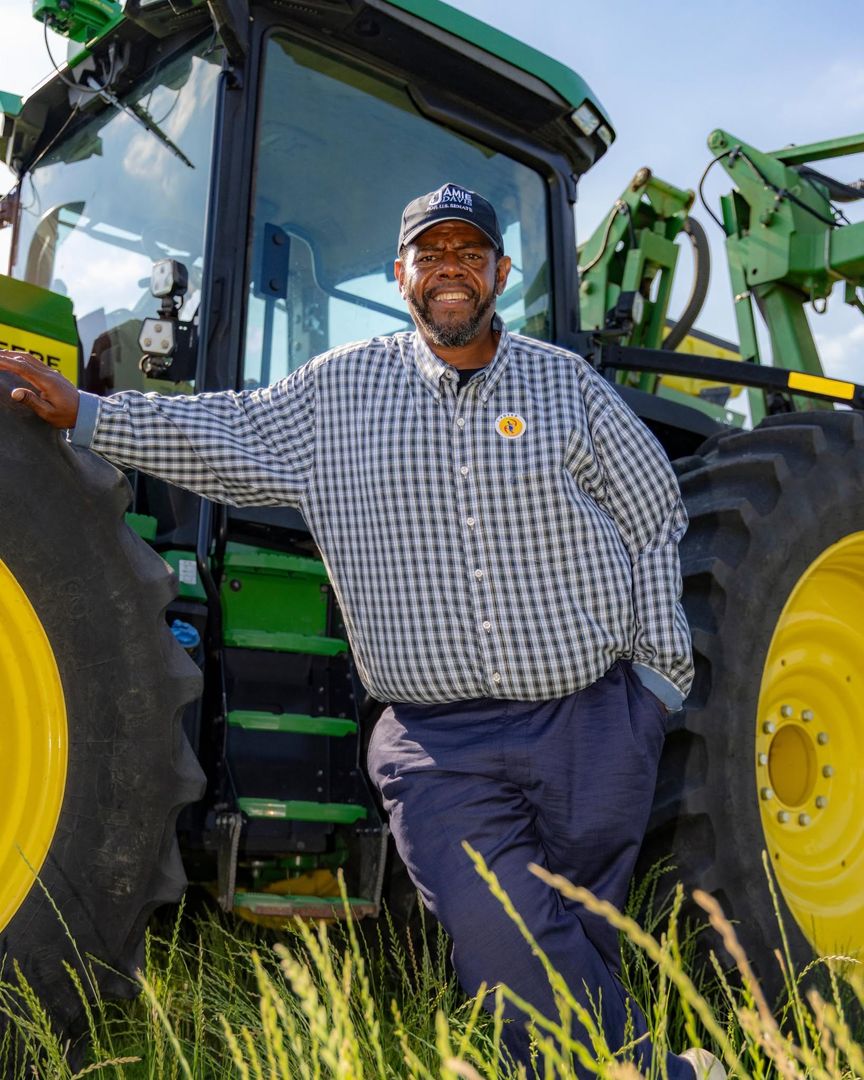 Jamie Davis leaning against a tractor in a Louisiana field